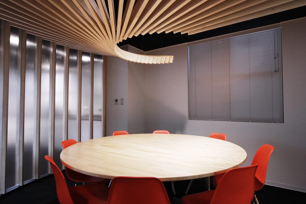 Sala de reuniones con mesa redonda y techo de lamas